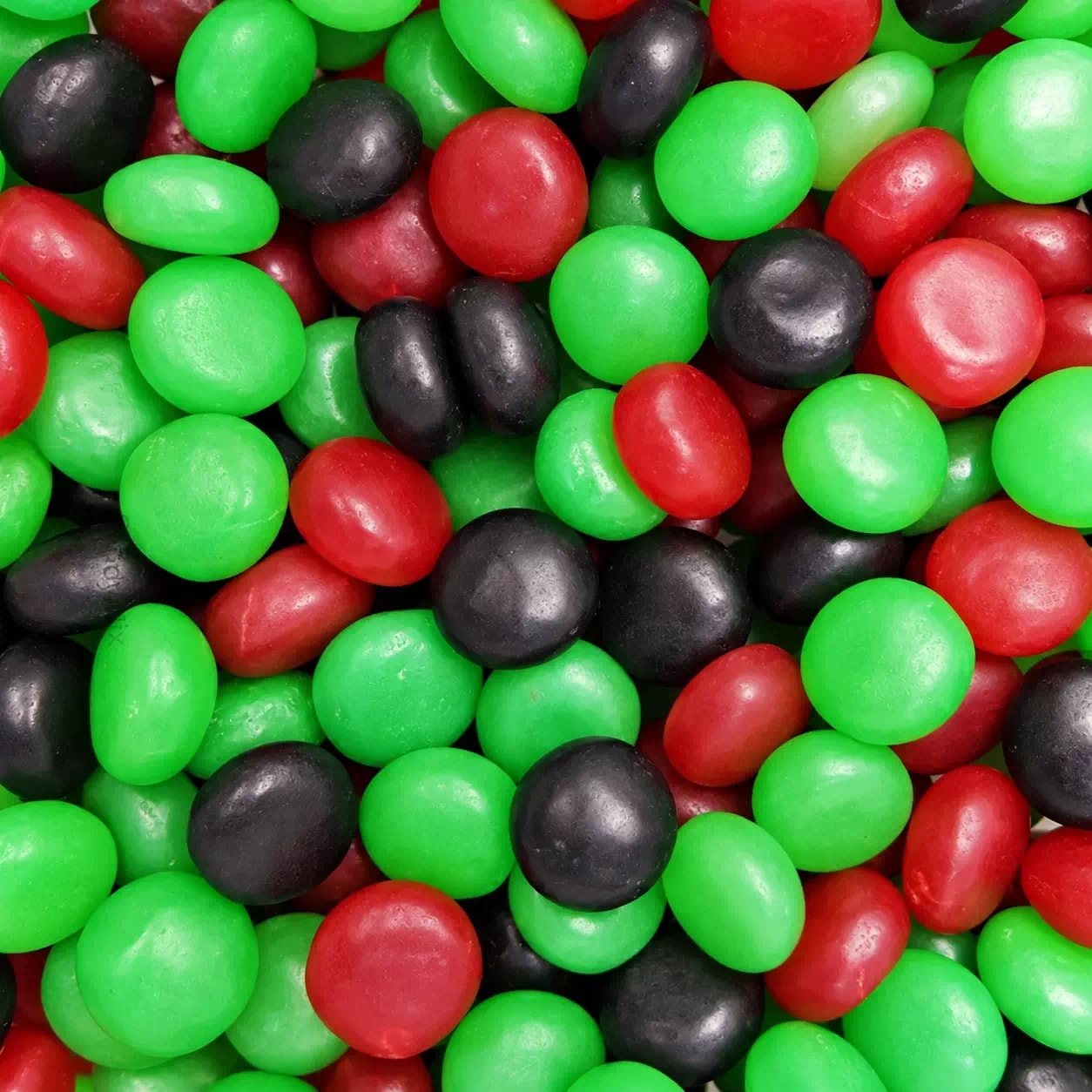 Pastilles gélifiées rondes vertes, rouges et noires, en vrac