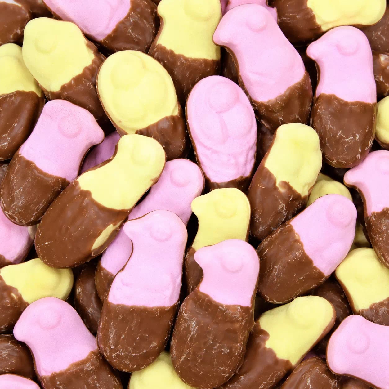 Guimauves roses et jaunes à demi trempées dans le chocolat au lait
